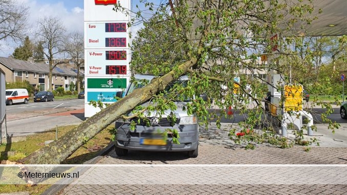 Boom beland op auto bij tankstation
