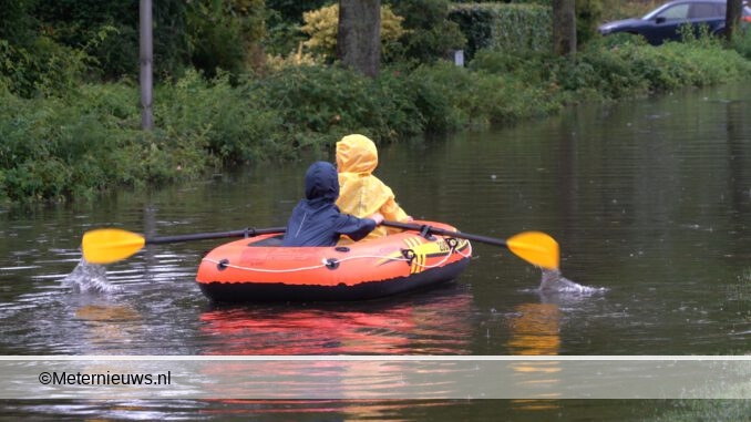kinderen roeienin Dalfsen door de straat wateroverlast